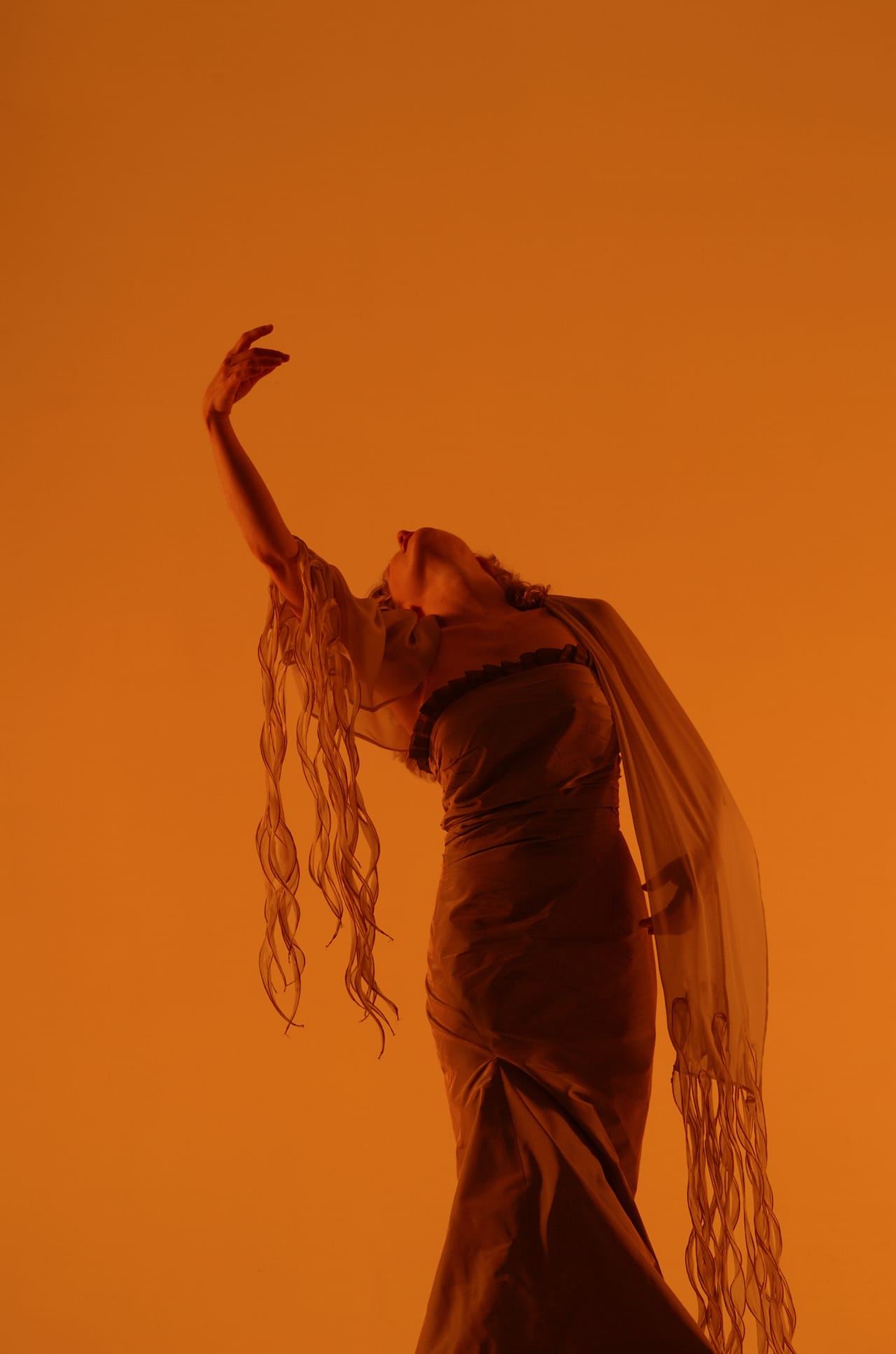 Suzie LeBlanc dancing over an orange background