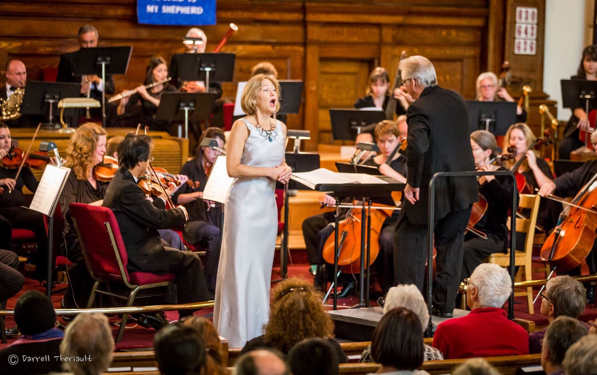 Suzie Leblanc signing on stage with a symphony orchestra